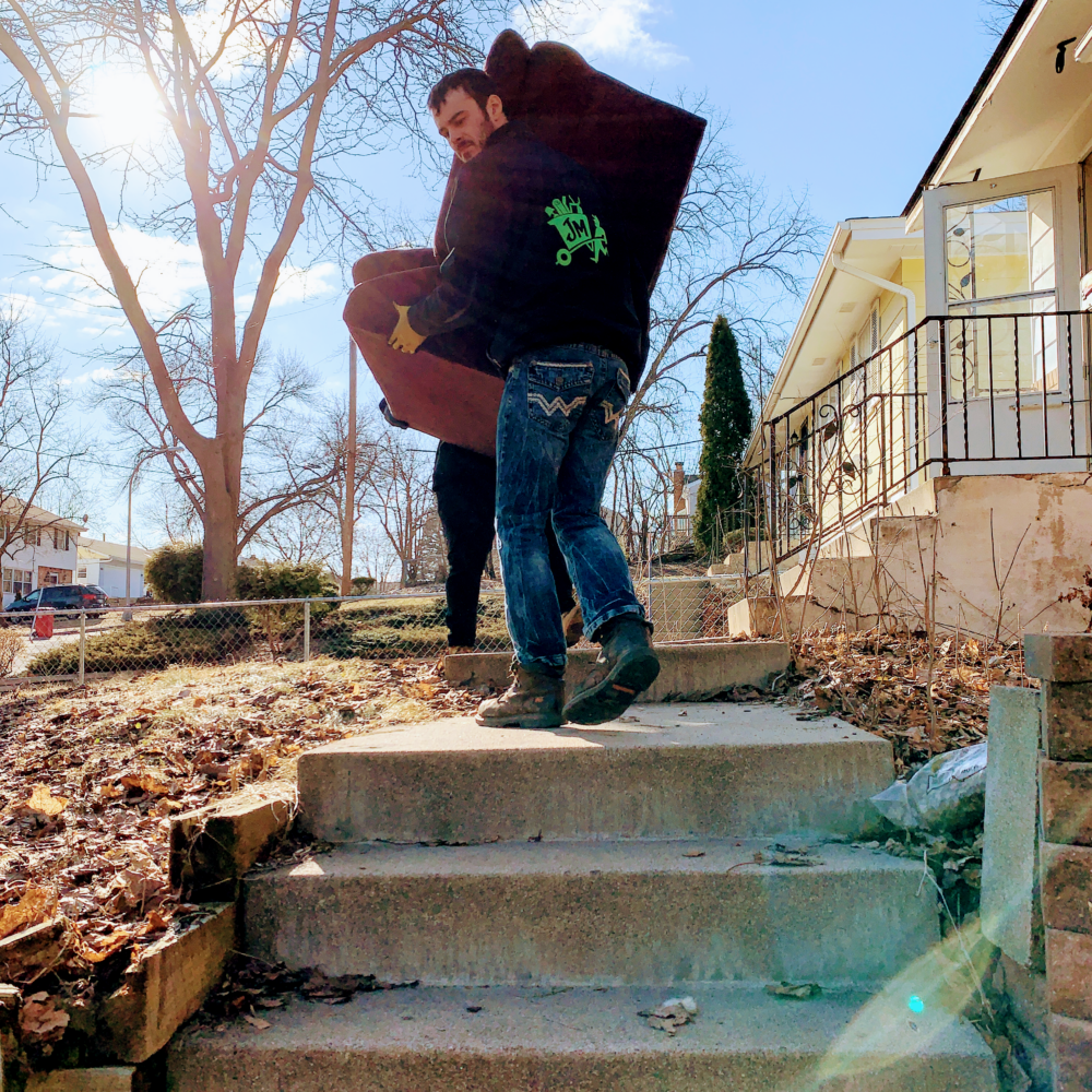 Junk Masters professional carefully hauling a couch down a set of stair during Shoreview junk removal services