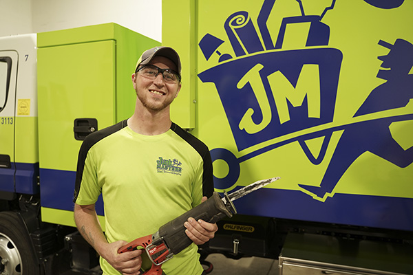 Junk Masters professional smiling with a hand tool ready to provide junk removal services in Minnesota